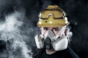 A rescue worker wears a respirator in a smokey, toxic atmosphere. Image show the importance of protection readiness and safety.